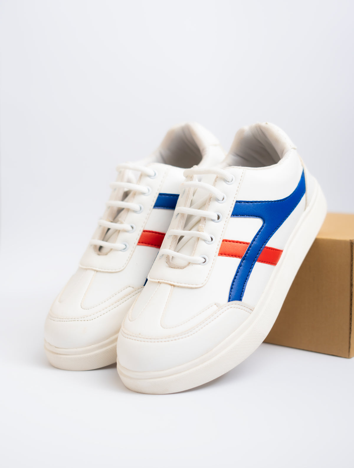 White sneakers with blue and red stripes on a light gray background