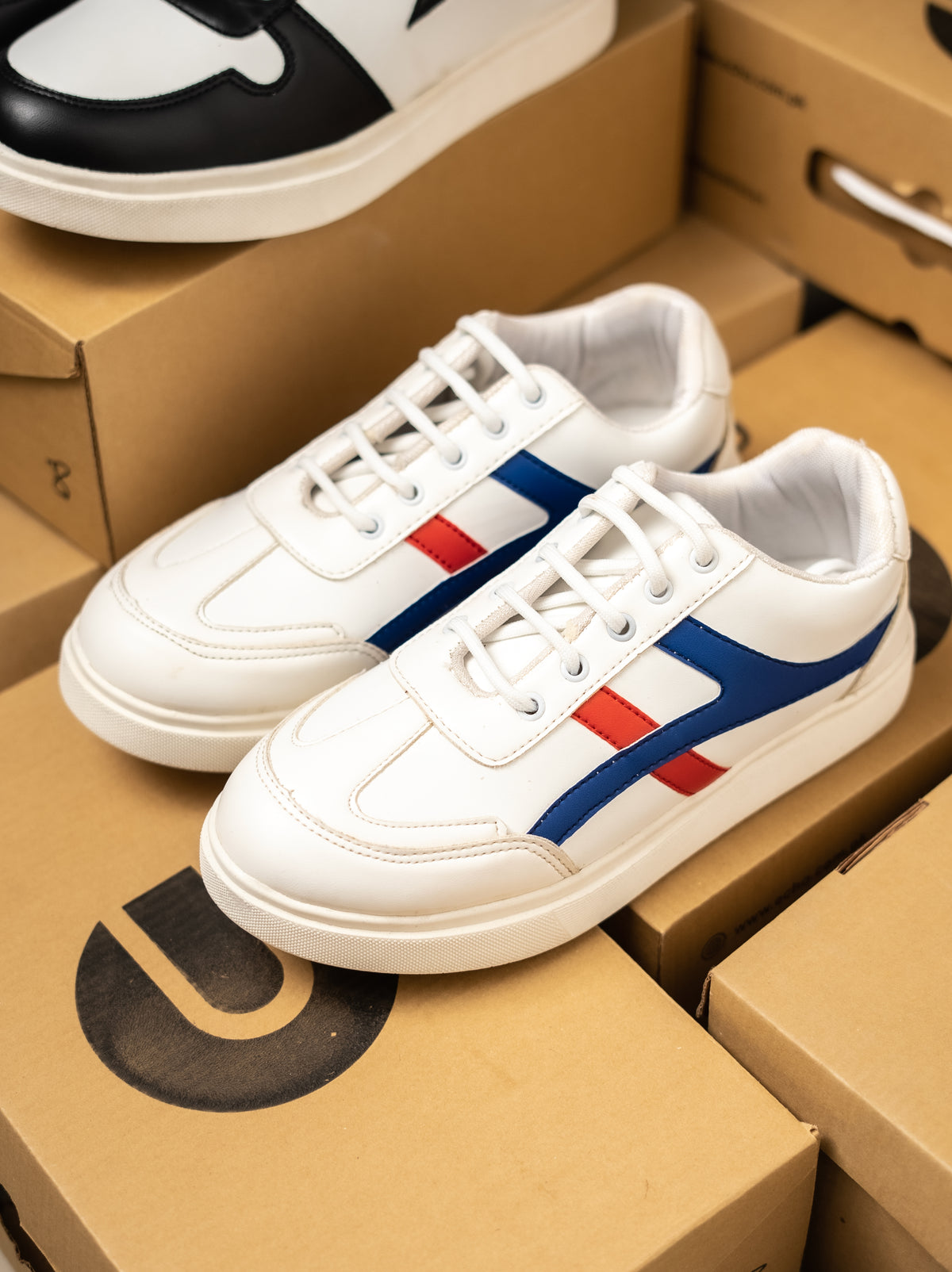 White sneakers with red and blue stripes on a cardboard box
