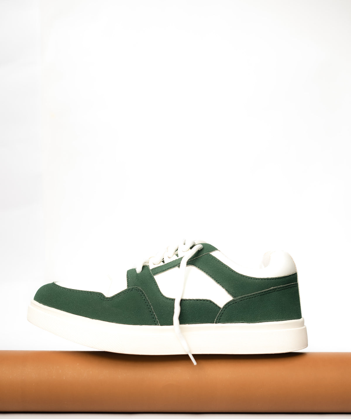 Green sneaker with white laces on a white background