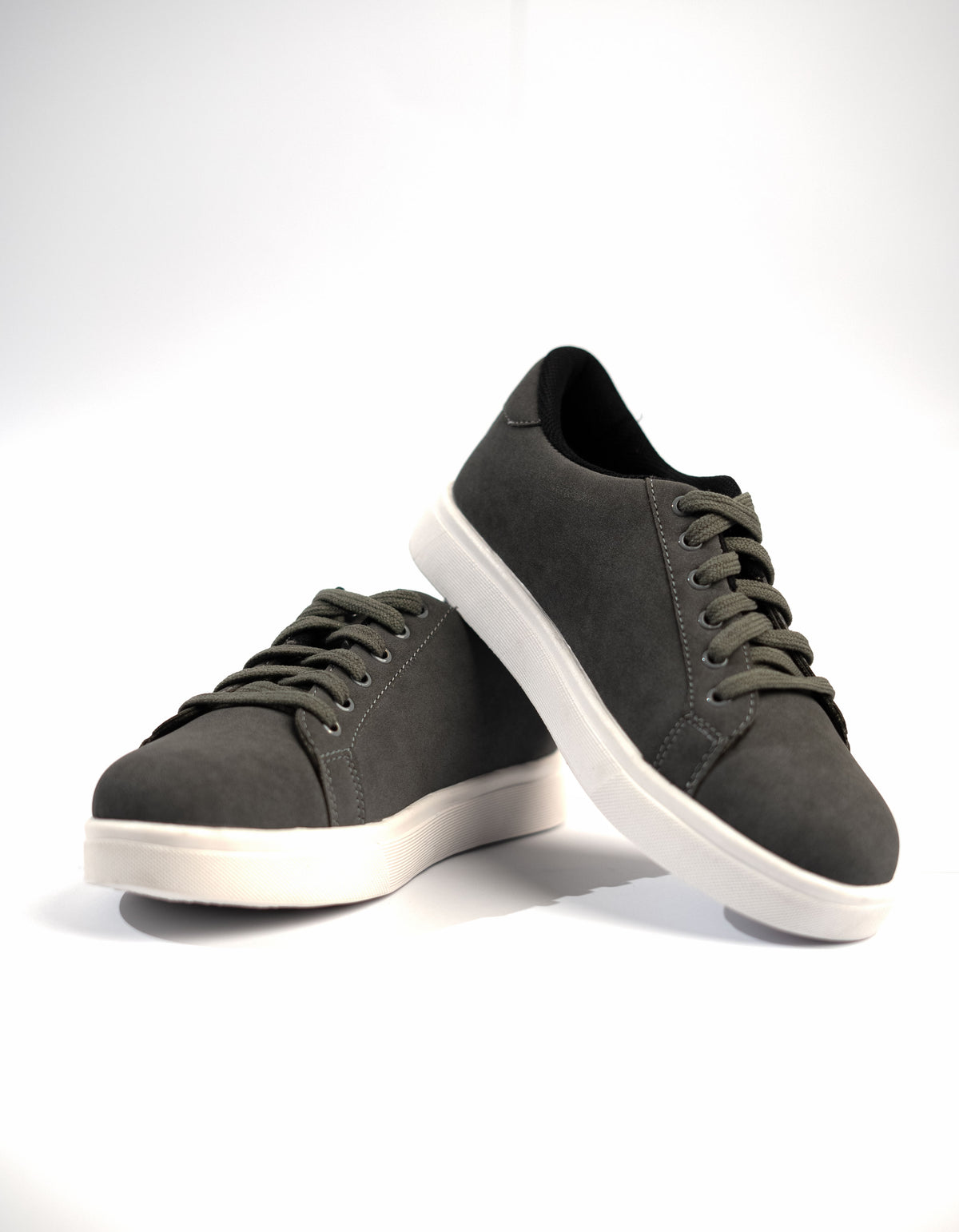 Pair of dark gray sneakers with white soles on a light gray background