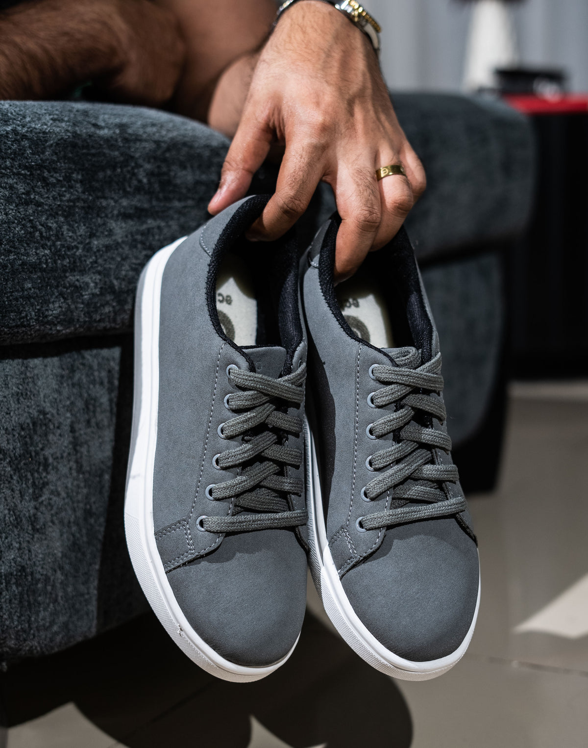 Person holding a pair of gray sneakers with white soles.