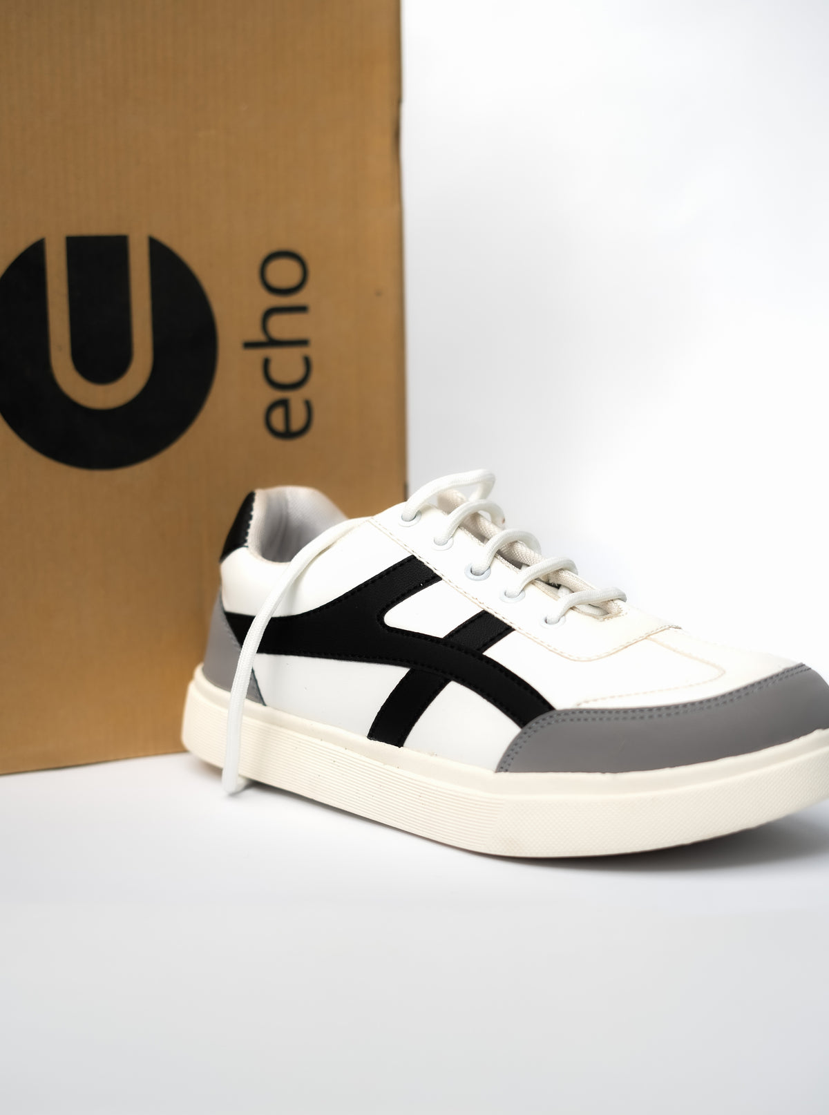 White and gray sneaker with black accents in front of an 'echo' branded box.