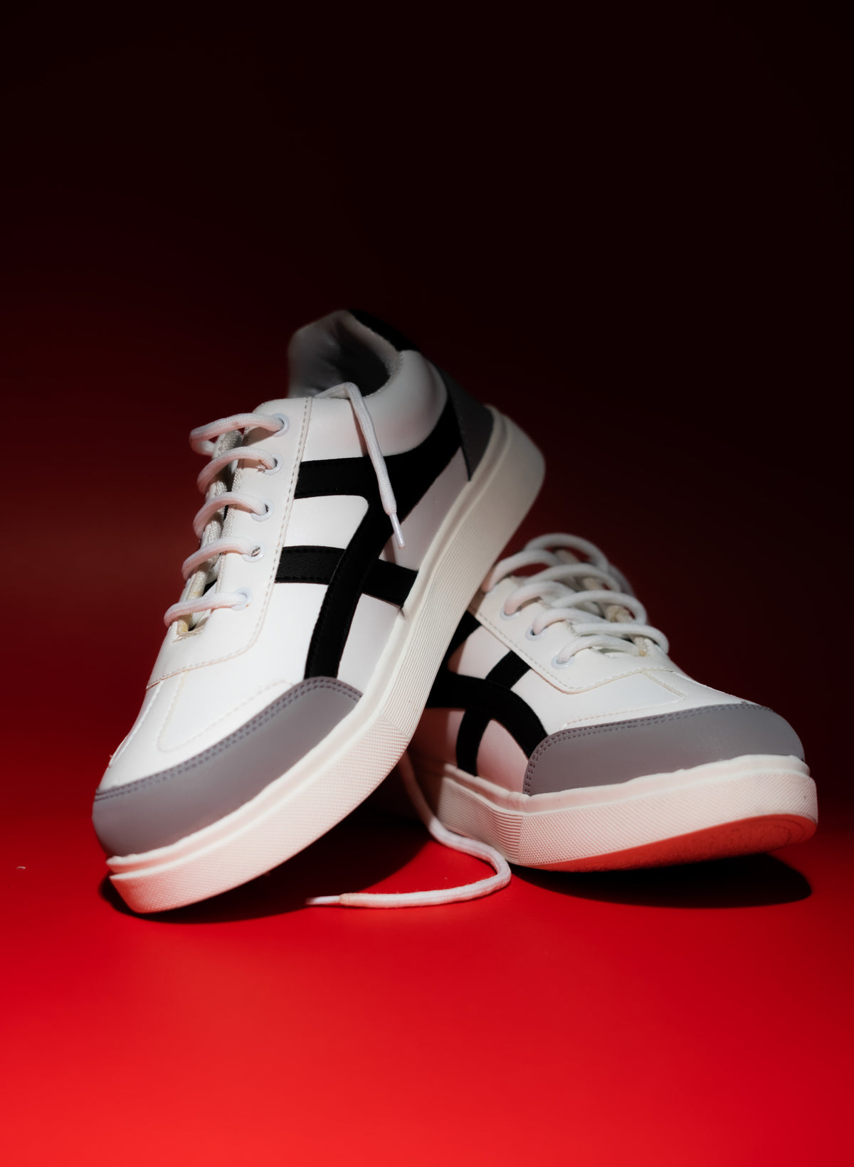 White sneakers with black and gray accents on a red background